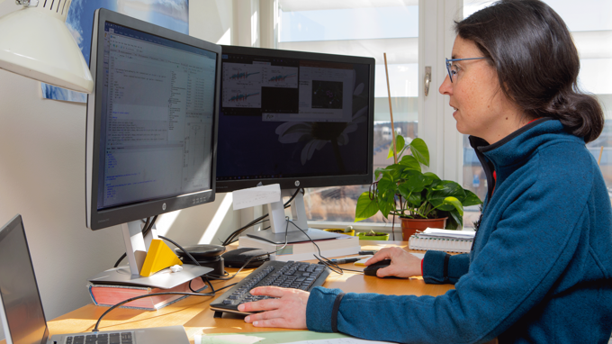 A woman with dark hair sitting in front of her computer programming.
