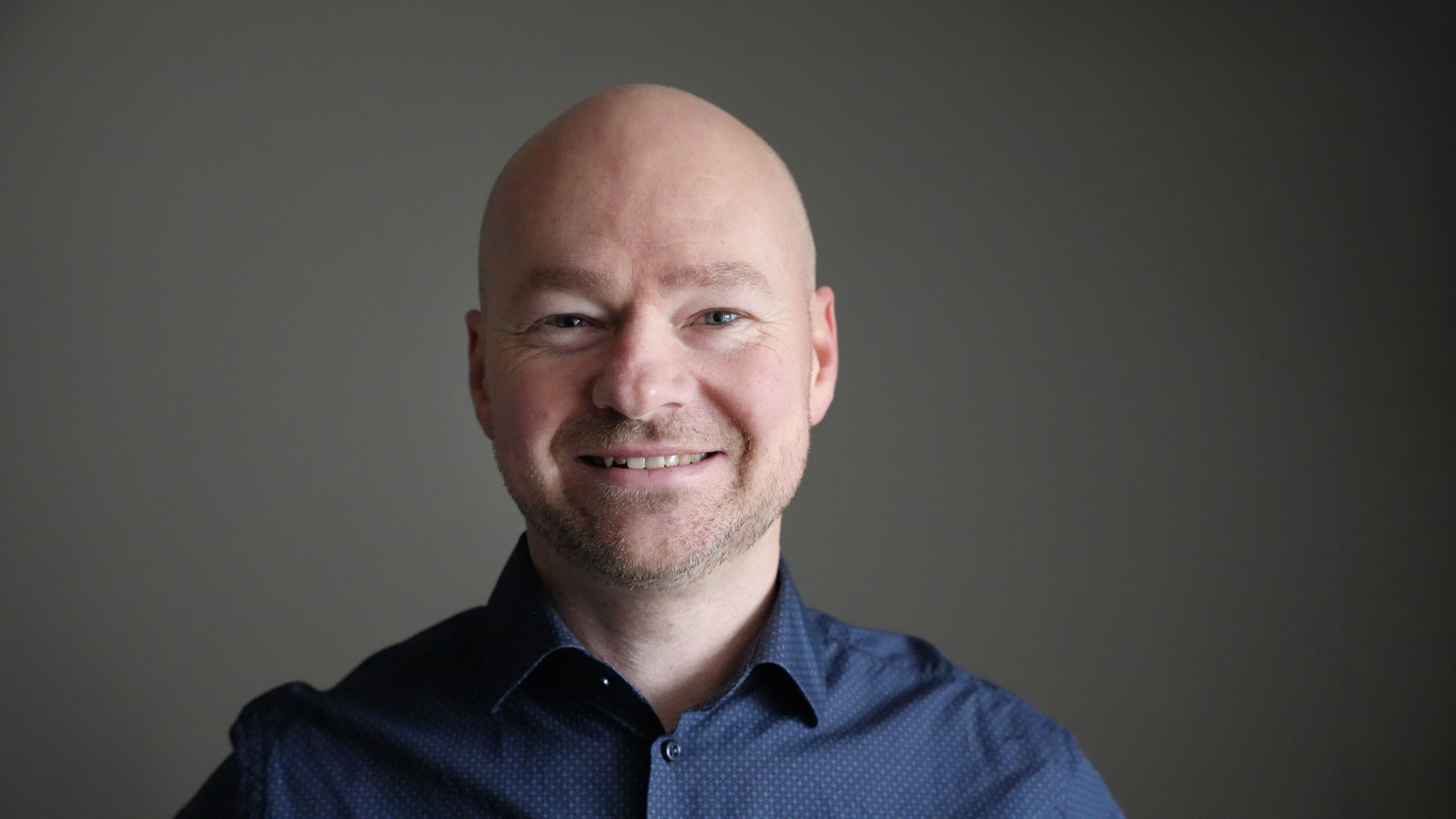 En leende man med grå skjorta.