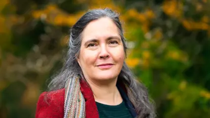 A person with long brown hair and a red coat