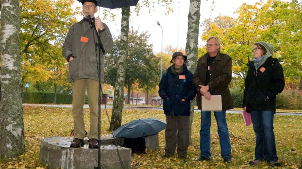 Person på podium som pratar under paraply