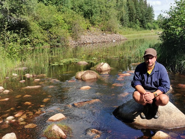 En man på en sten i en bäck.