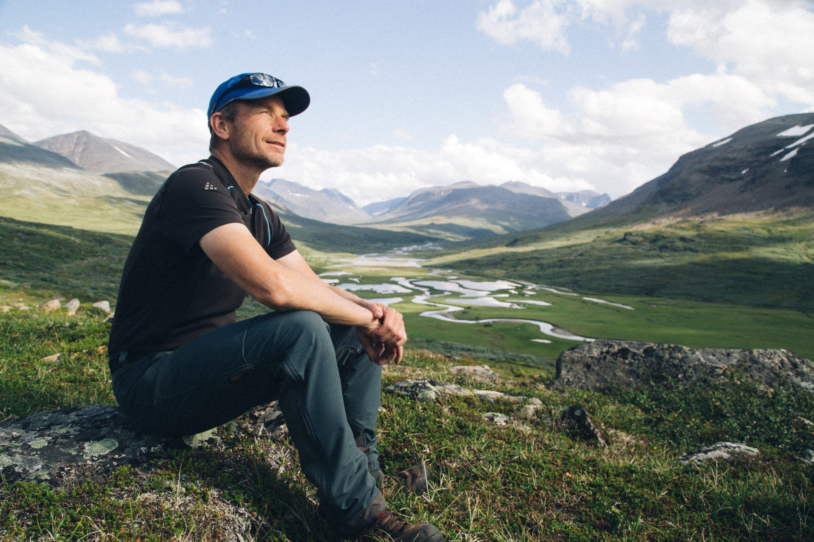 En man sitter på en sten i fjällen