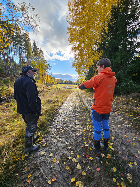 Två personer pratar på en grusväg