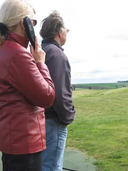 Besökare med audioguide-lur i utomhusmiljö.