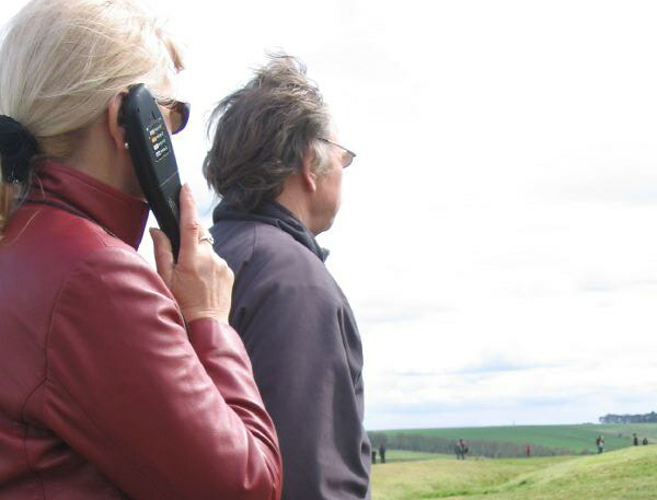 Besökare med audioguide-lur i utomhusmiljö.