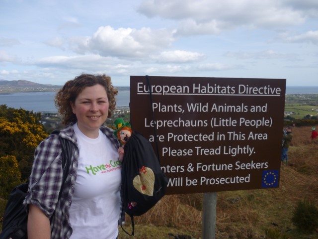 Kvinna vid skylt i naturen med hav i bakgrunden