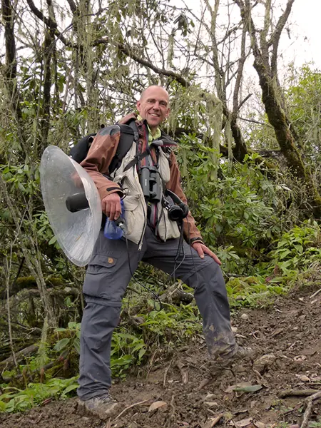 Person med parabolmikrofon i skogsmiljö.