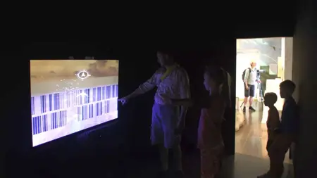 En skärm i ett rum med personer som tittar på den