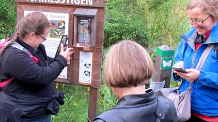 En grupp besökare som provar mobilguide vid naturstig