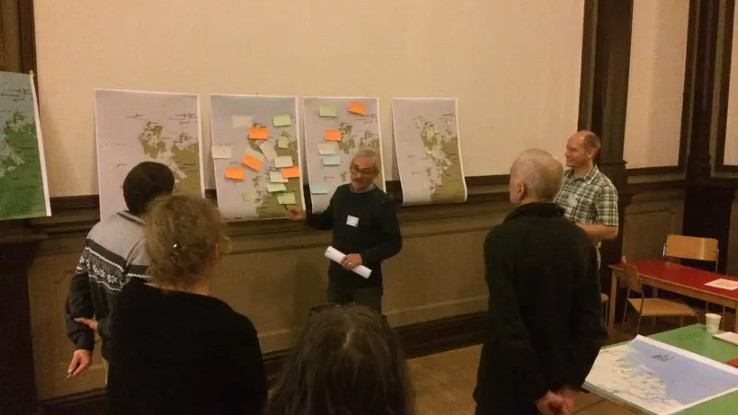 Personer pratar framför en vägg med papper på