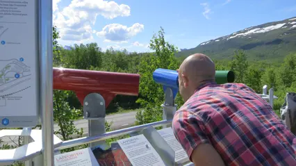 A man looking at the view through a tube