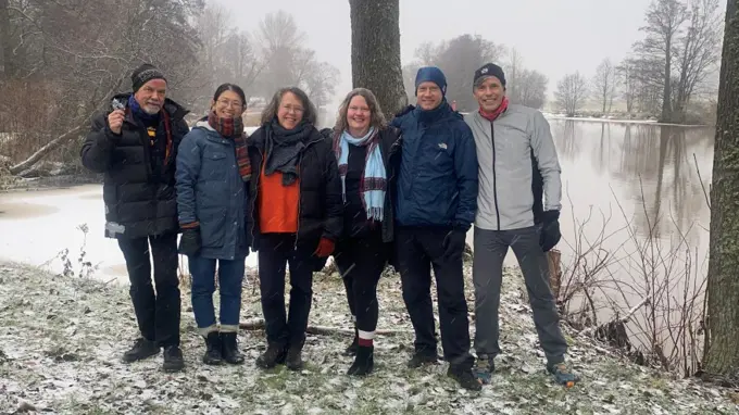 Sex personer står vid en å