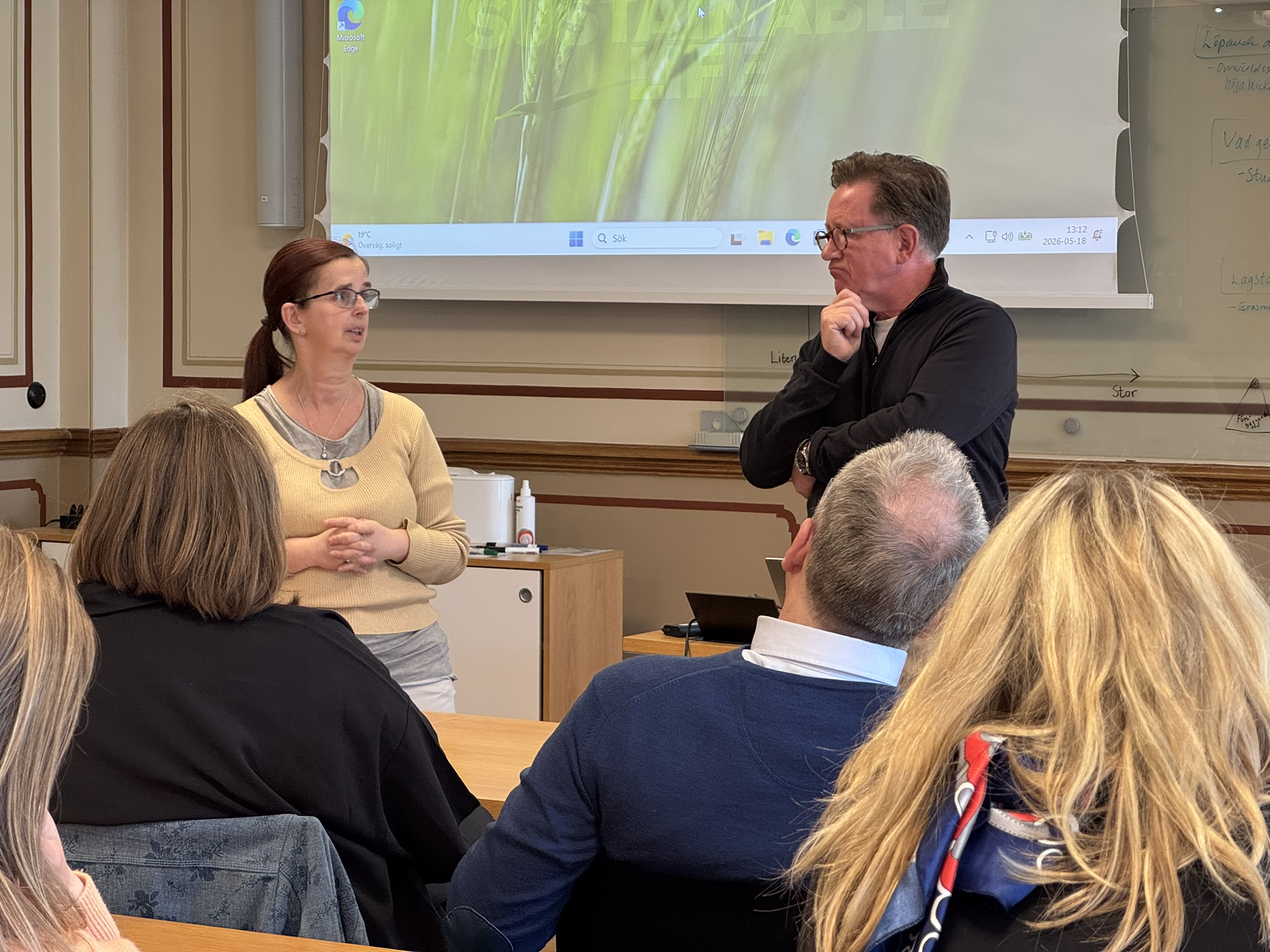 En kvinna och en man presenterar inför publik.