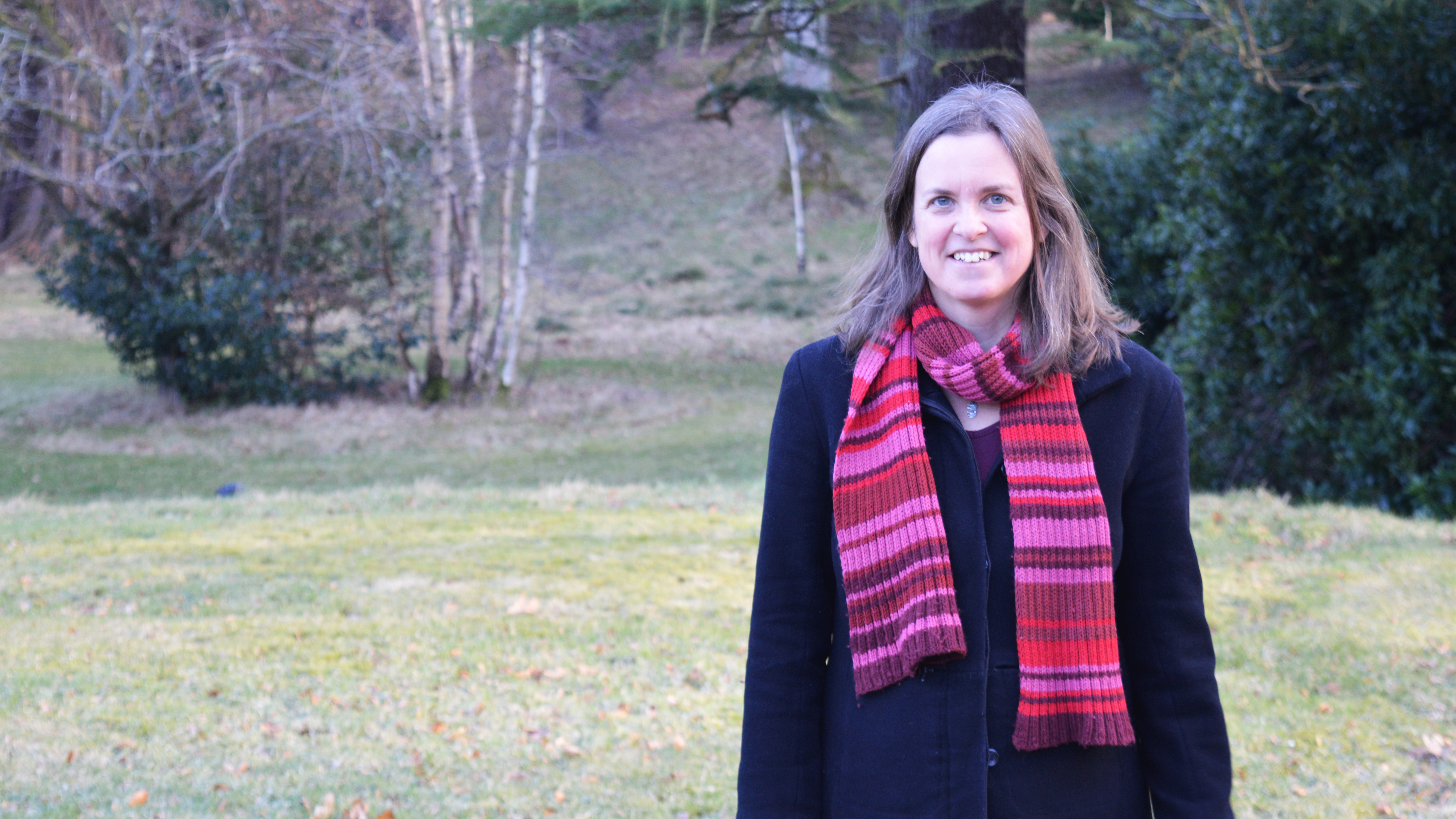 En kvinna i en mörk kappa med en rödmönstrad halsduk. Foto.