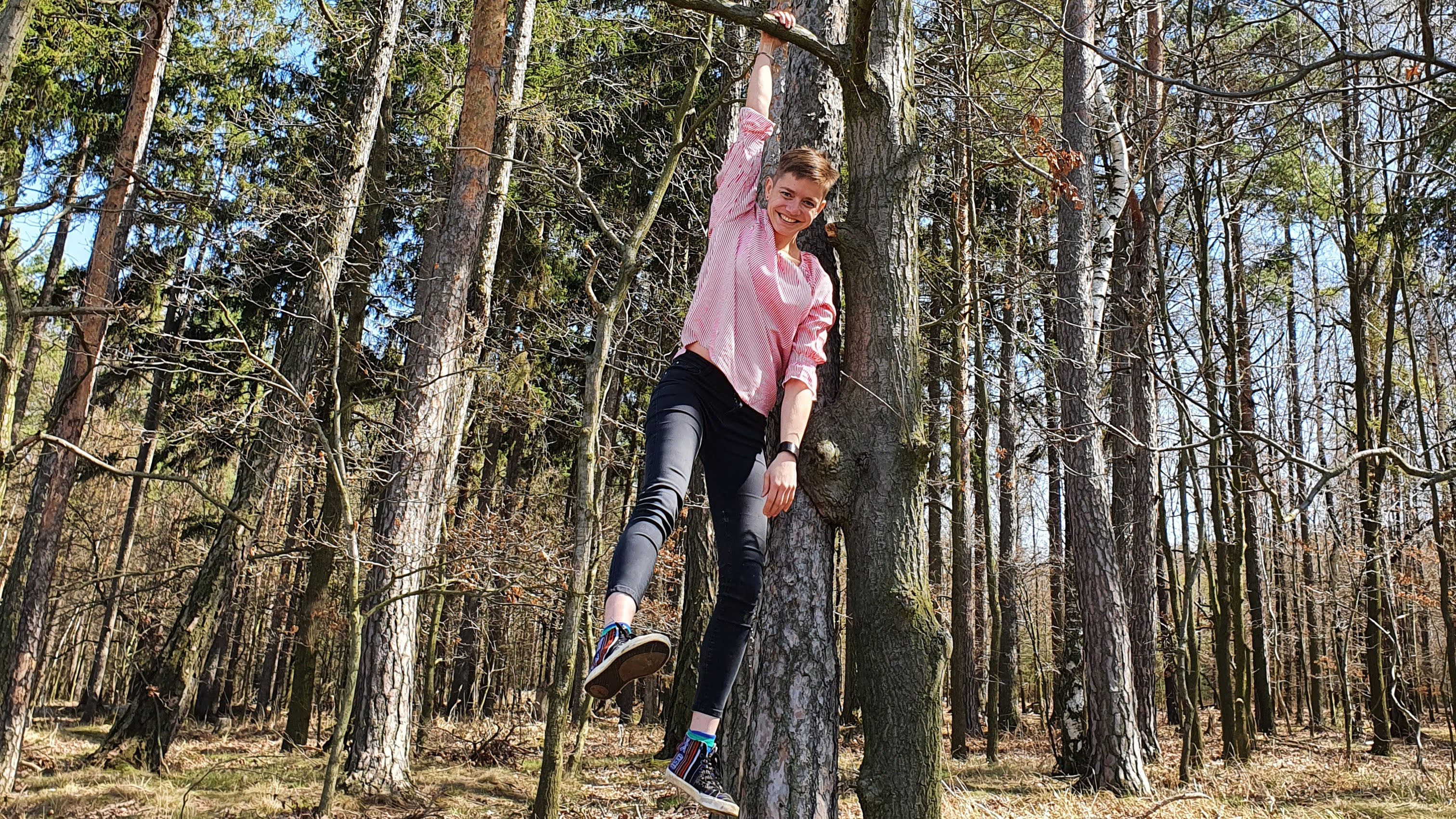 En kvinna hänger med en arm i ett träd. Foto.