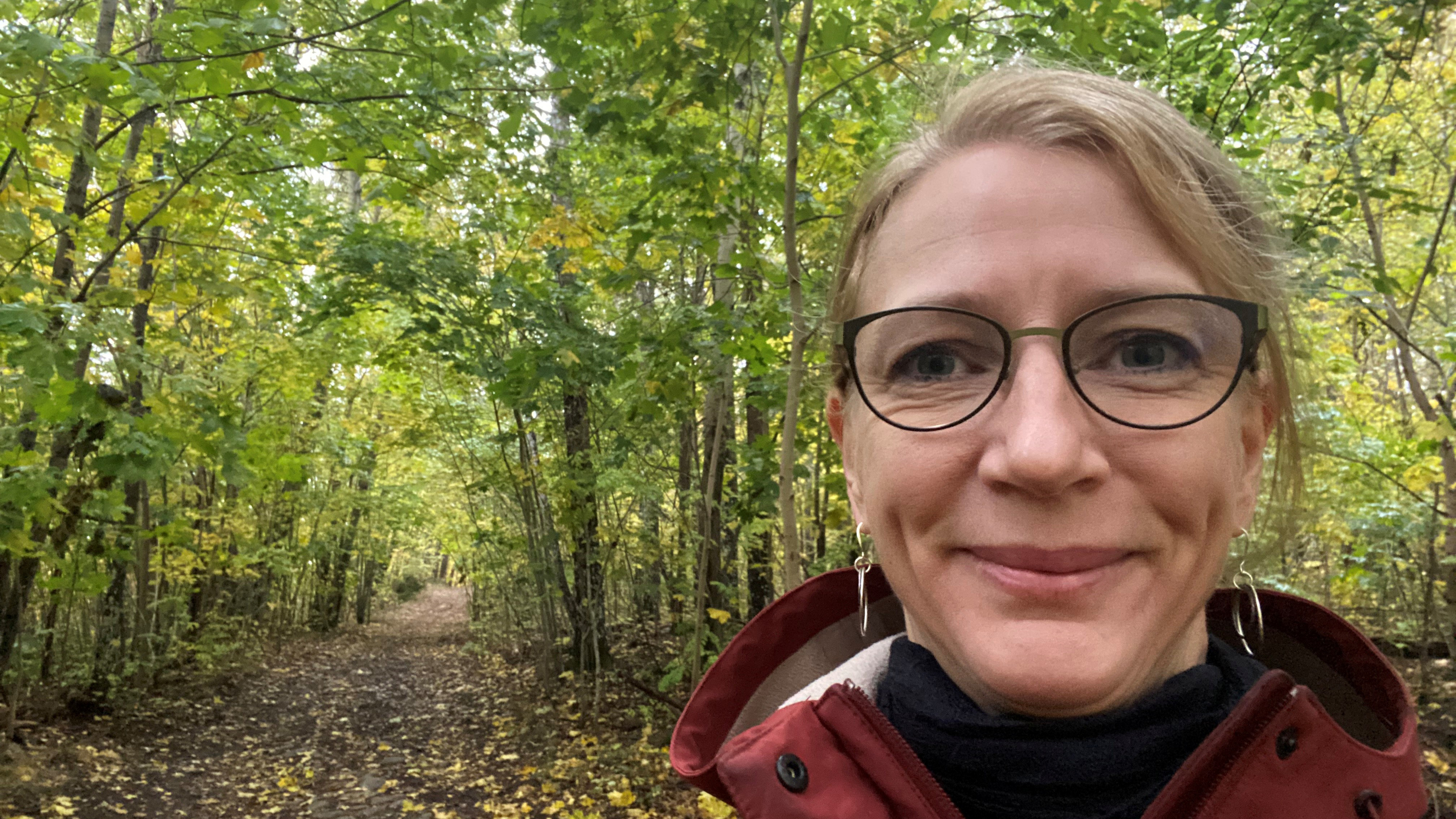 En glad kvinna i skogen. Foto.