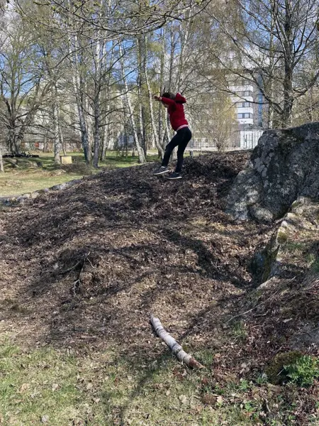 A child is running around and jumping on a rock in a playful outdoor setting.