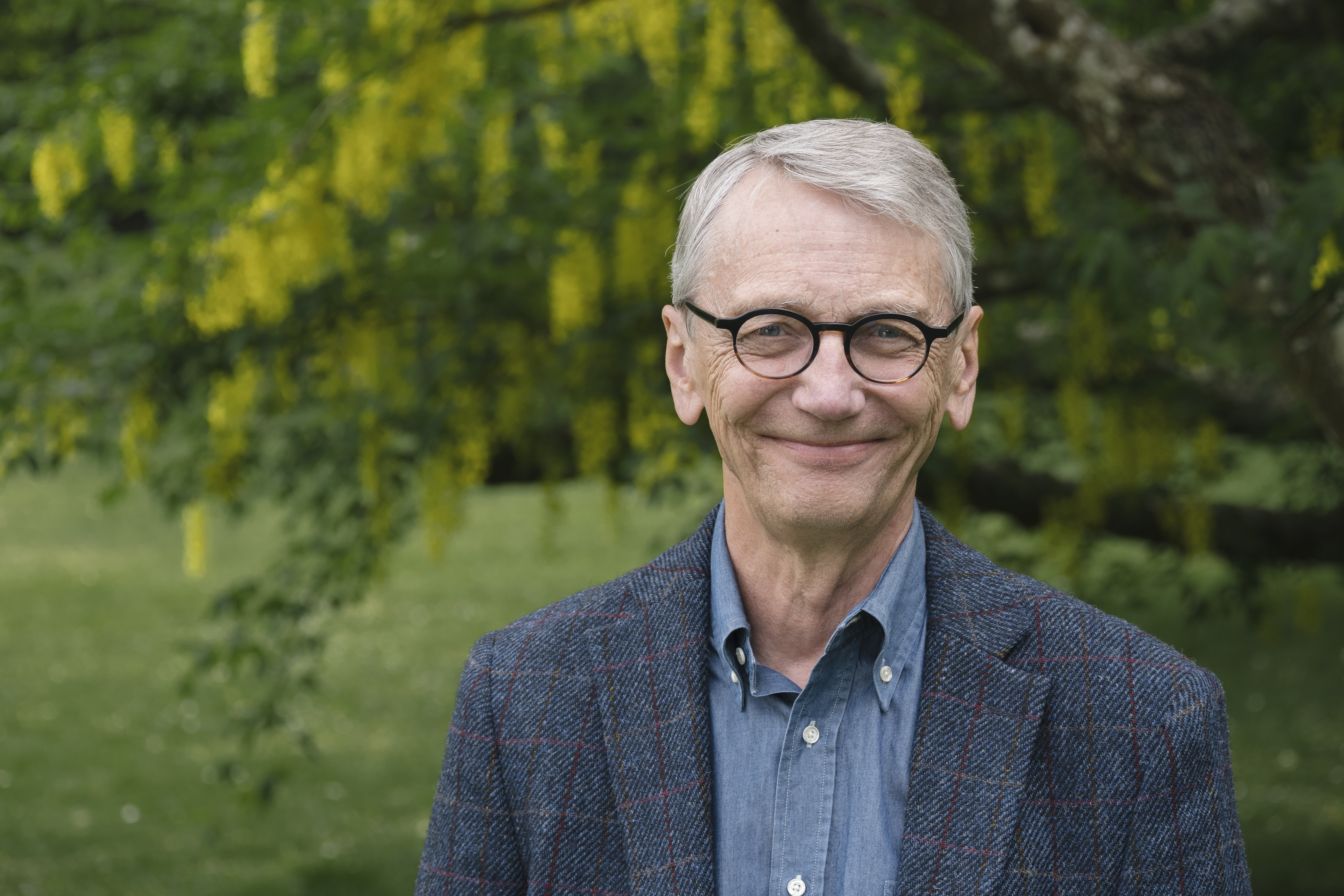En leende man framför grönska