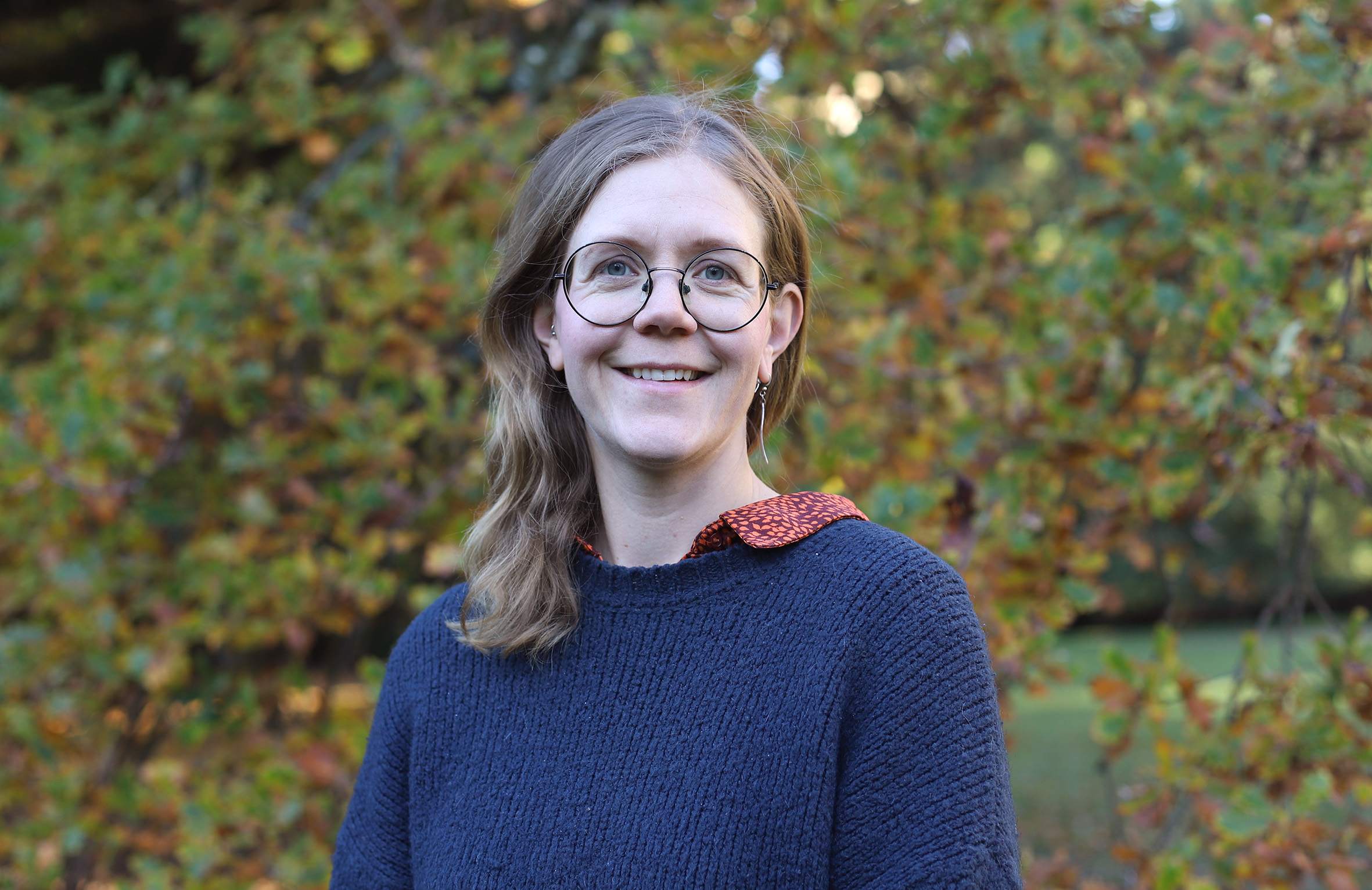 En kvinna som ler framför grönska