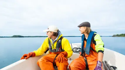 Två personer sitter i en båt och ser glada ut.