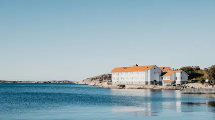 The picture shows the exterior of the Sea Fish Laboratory in Lysekil. The building has a white/blue facade and is located by the sea. The sun is shining.