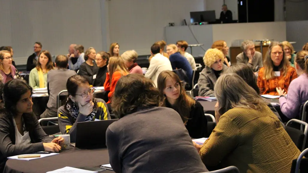 Forskare sitter runt runda bord vid en forskarkoferens