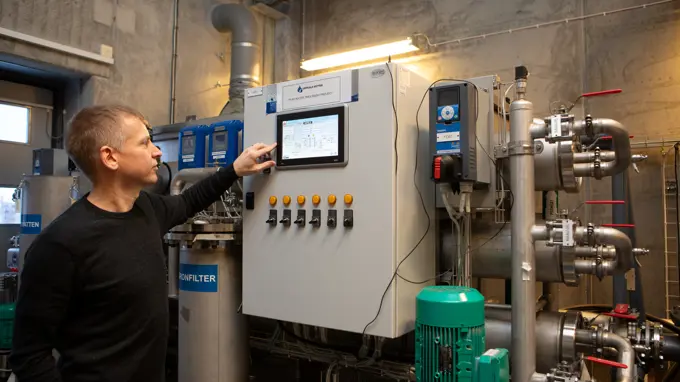 A person standing in front of some technical device, pushing one of the buttons.