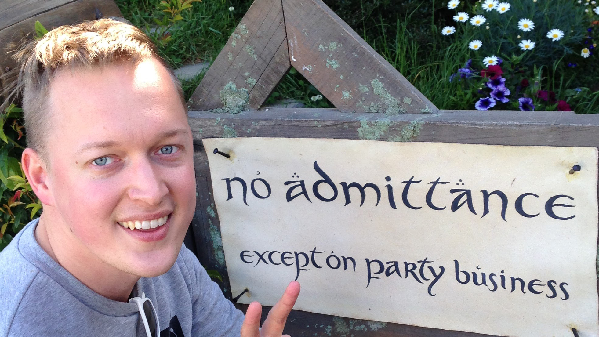 Henrik poserar framför en skylt som säger "No admittance except on party business".