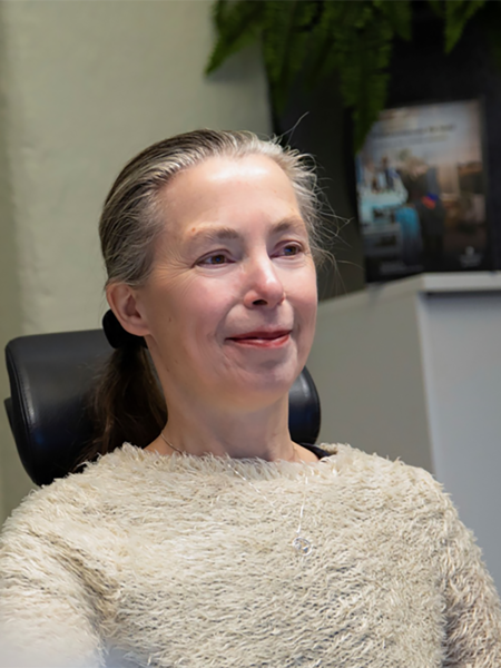 Kvinna med håret samlat i svans, beige stickad tröja