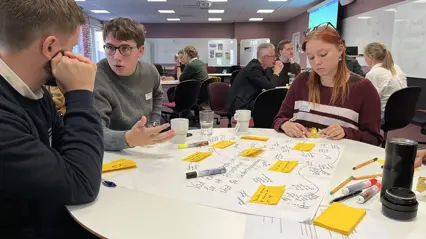 studenter diskuterar vid runt bord