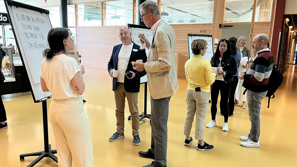 människor står och samtalar vid ett blädderblock