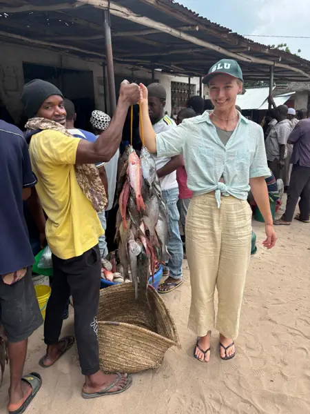 Two persons holding a rope with fish