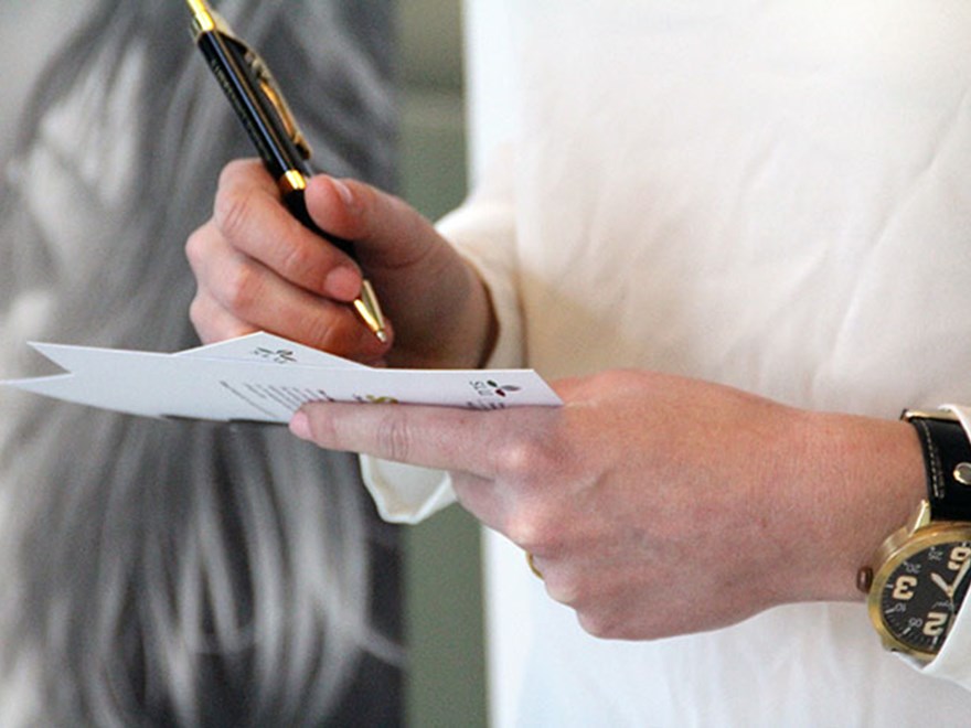 Närbild på en person som håller i ett dokument och penna, foto.