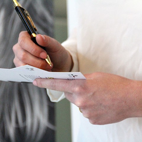 Närbild på en person som håller i ett dokument och penna, foto.
