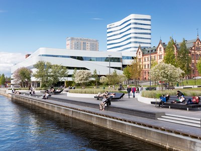 Summer in Umeå, people sit on park benches and stroll along Umeälven, photo.